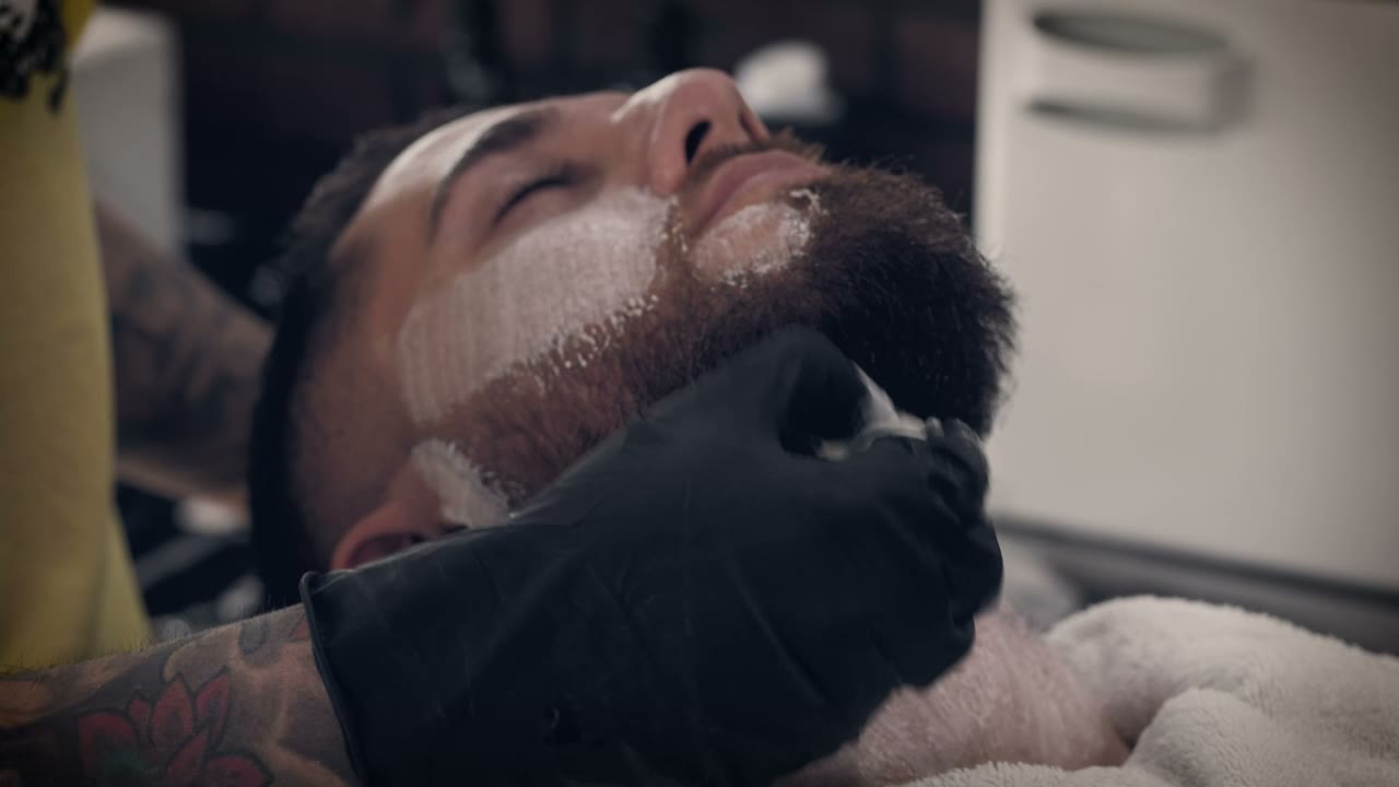 Client with warm lather on his beard before a straight razor shave