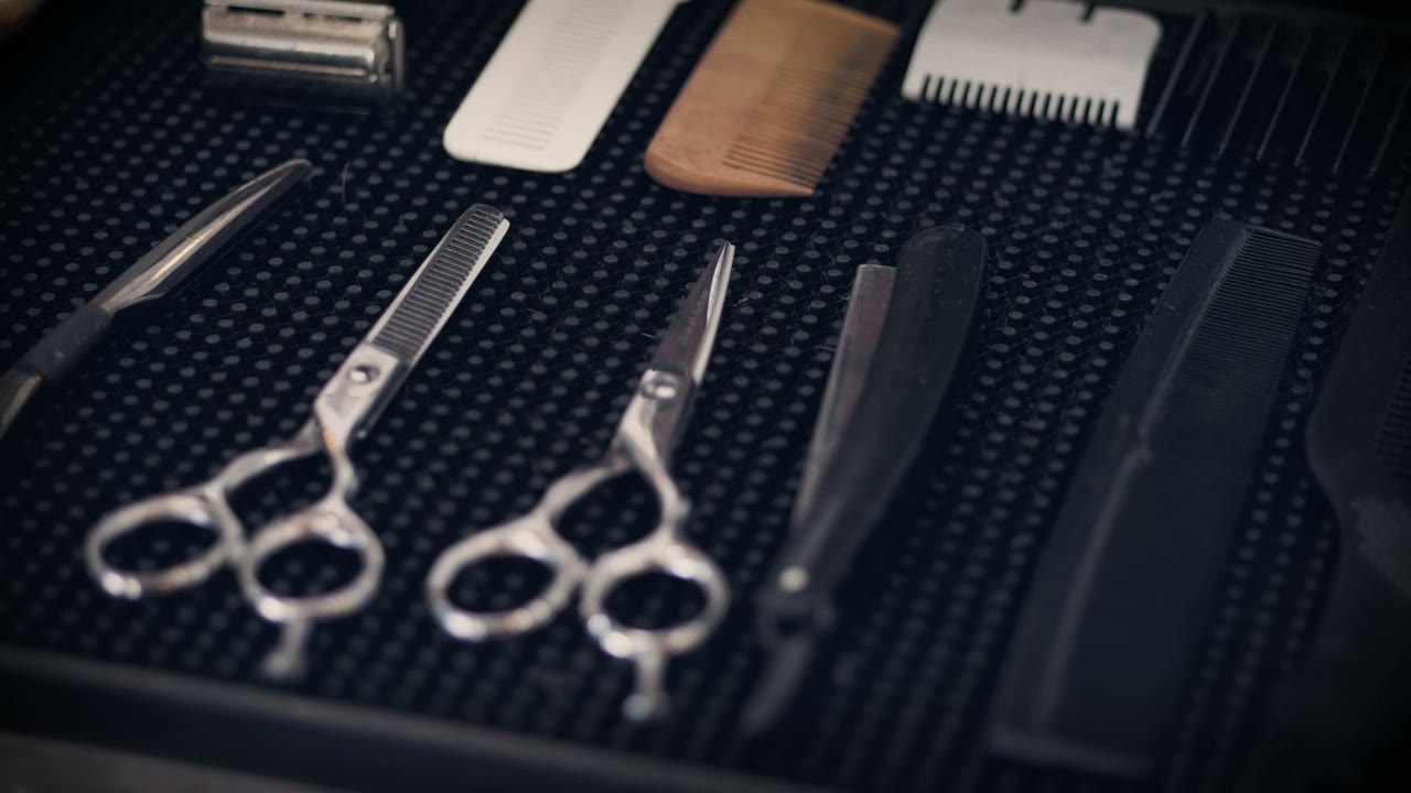 Barber's scissors, razor and combs laid out on a mat